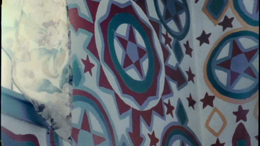 A close up of blue retro wall paper designs with floral curtains on the window corner