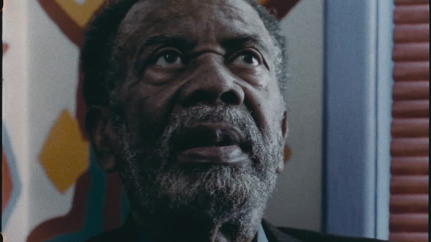 An old man in a room appearing nervous and anxious his face is tilted upwards suggesting he might be contemplating or anticipating something with apprehension