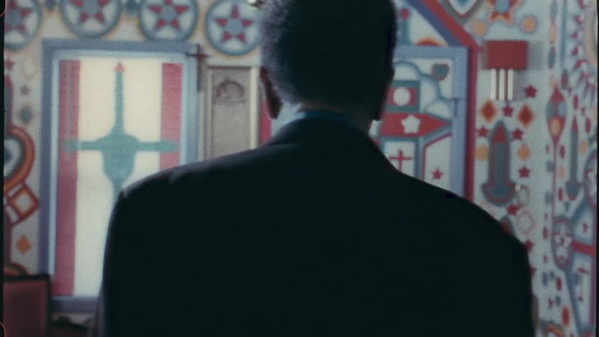 The backside of an elderly man walking into a bright and colorfully painted room