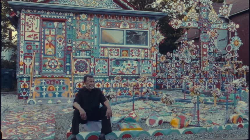 Uniquely painted house known as prophet isaiahs second coming in niagra falls with an older man sitting in the foreground