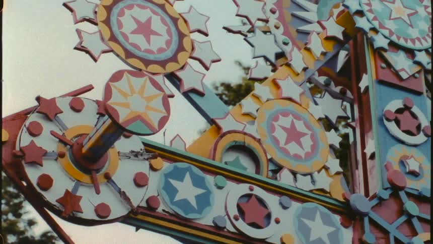 A colorfully painted machine ride outdoors near trees
