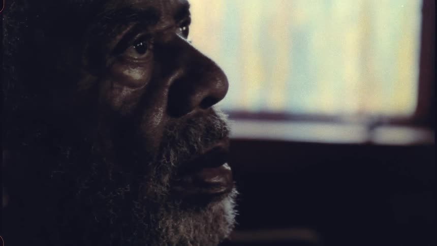 An older man looking straight ahead contemplatively his face close up