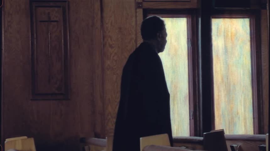 Man with black overcoat walks in the church