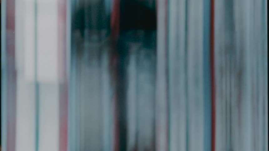 Distorted footage of moving objects behind a screen of colorful vertical lines