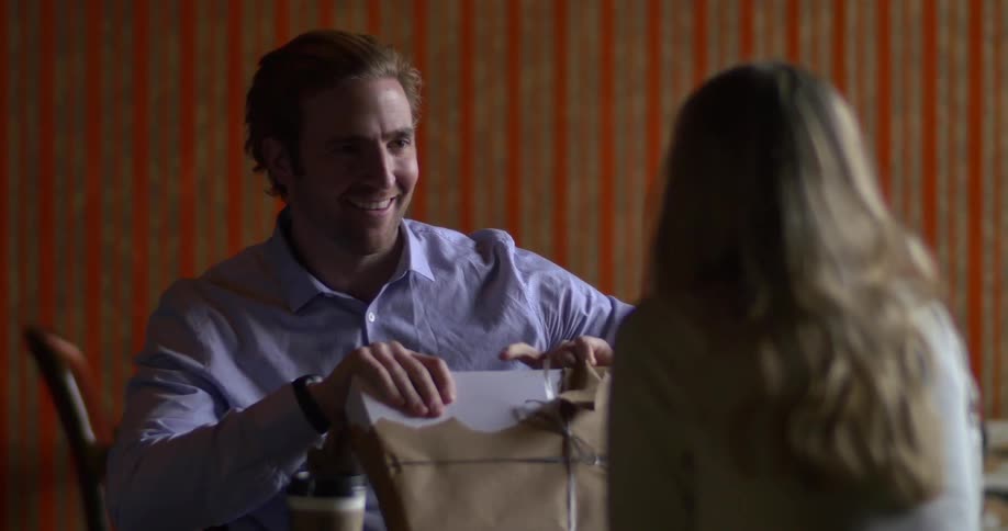 A man unwraps a present with a woman