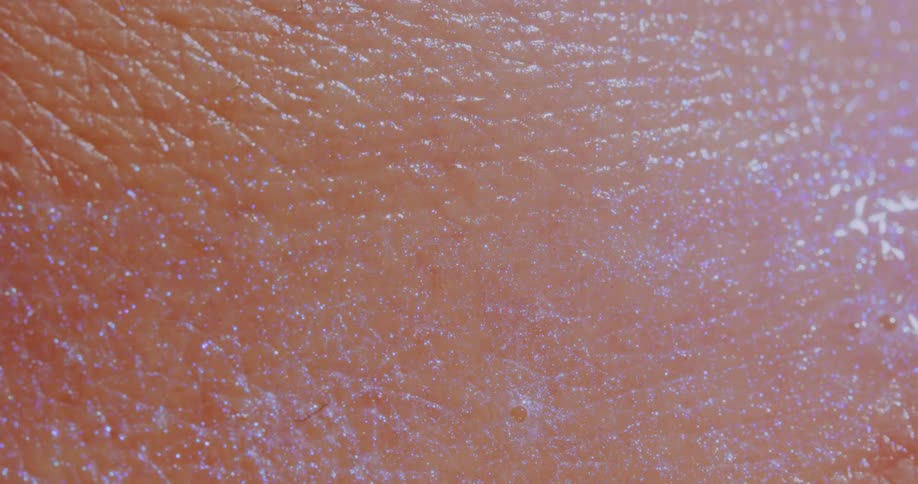 Light reflects on a pink textured sparkling liquid surface as it moves