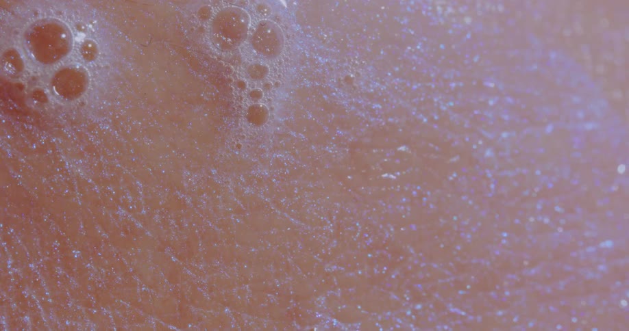 A closeup view of water and soap suds on human skin
