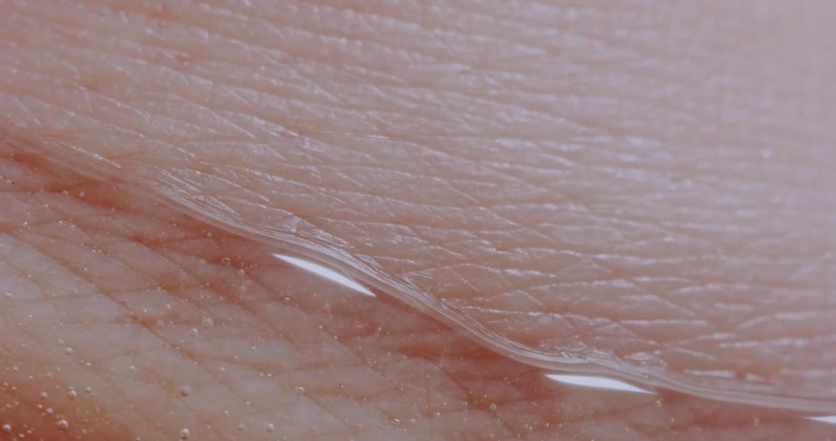 A close up of a persons skin with clear liquid slowly moving over the skin