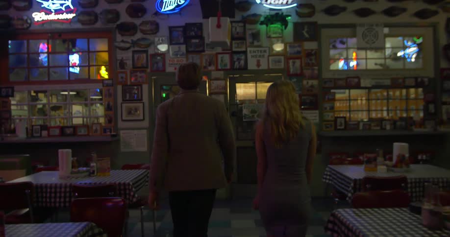 A man and woman walking inside a restaurant at night