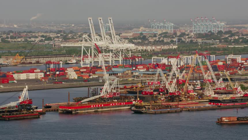 A working dock with several cargo boats and both loaded and unloaded containers and a road leading to it