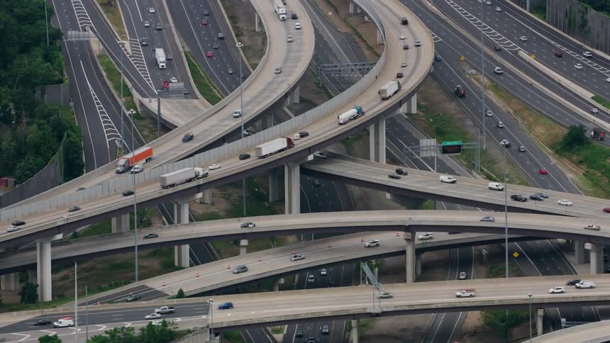 Cars and trucks travel on a super highway junction around curves and bridges