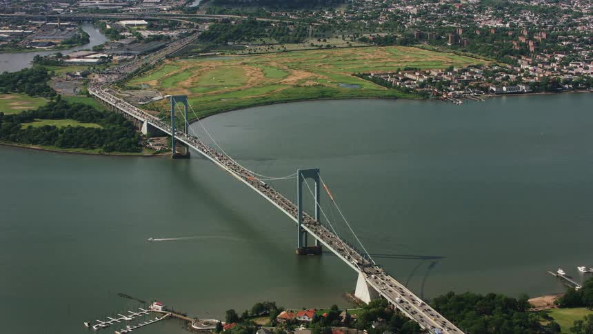 Heavy traffic passes down a bridge over a river in the suburbs