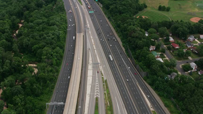 Vehicles drive down a multilane highway past the suburbs