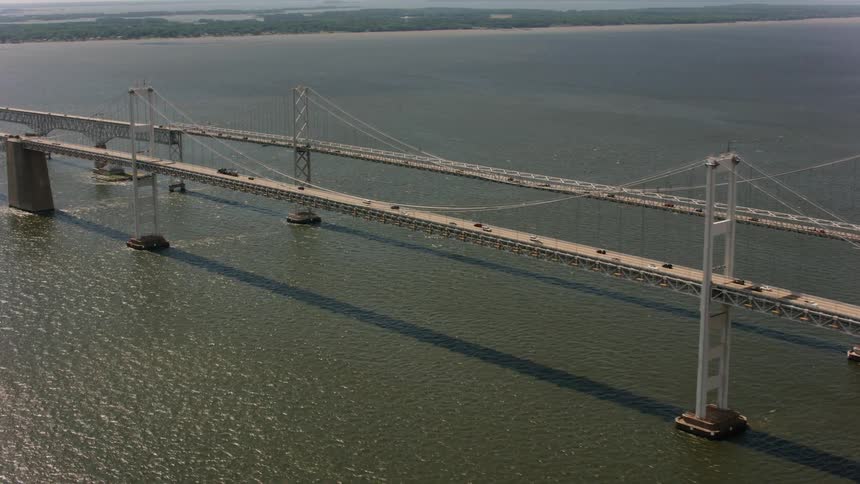 Drone view of two long bridges side by side over open waters near land