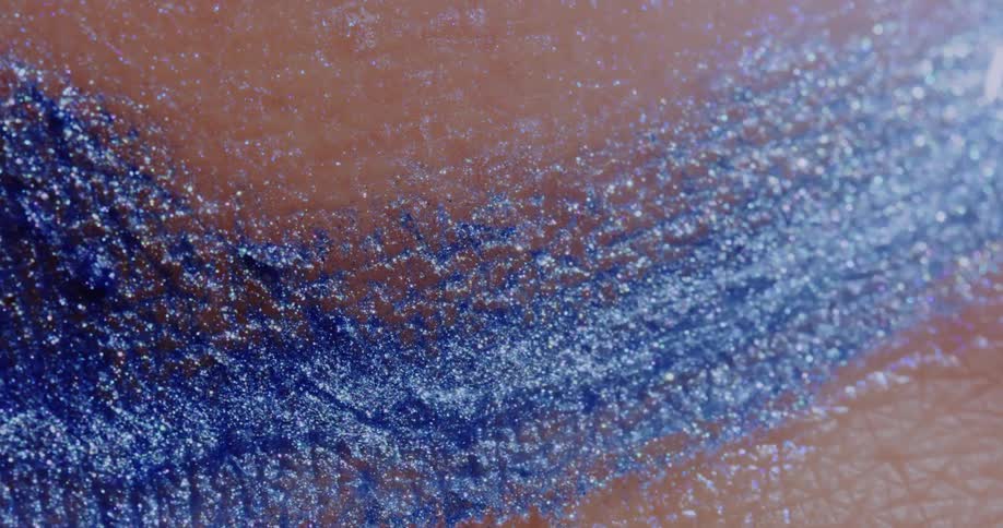 Close up of blue glitter slowly moving over a persons skin