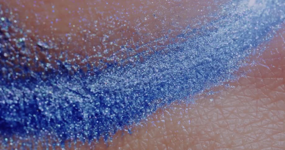Glittery blue liquid running over human skin