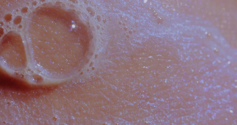 A closeup view of soap suds and water on human skin