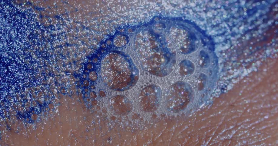 Bubbles in glittery blue ooze on human skin