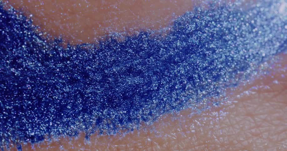 Blue glitter shimmers on a persons skin