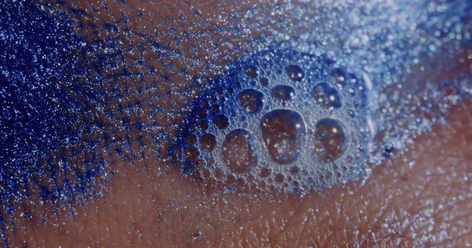 Shimmery blue soap bubbles on a persons skin