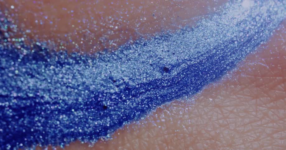 Gleaming blue and silver mixture flows across textured peach skin