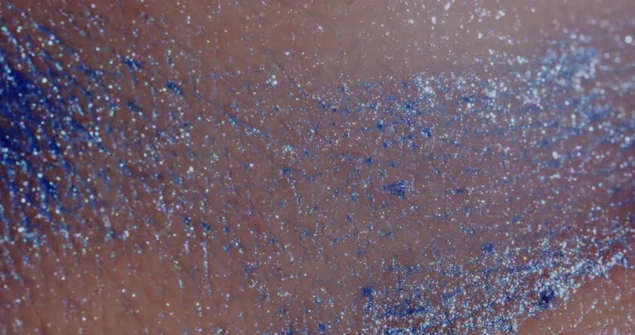 Glitter shimmers while spread across a persons skin