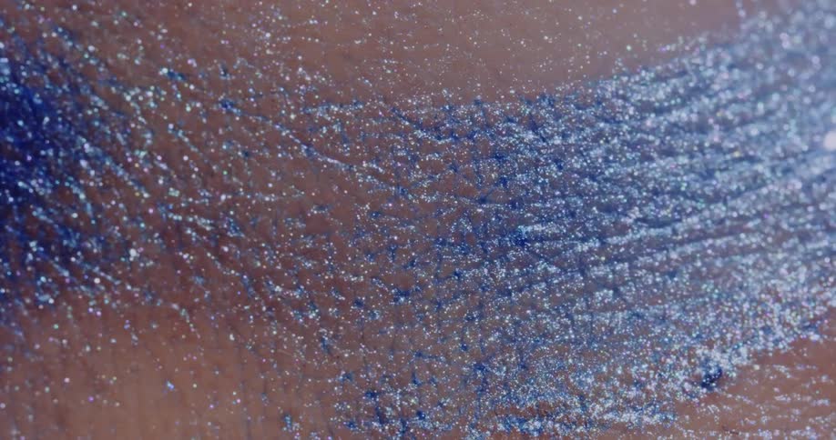 Blue glitter is smeared against a persons skin