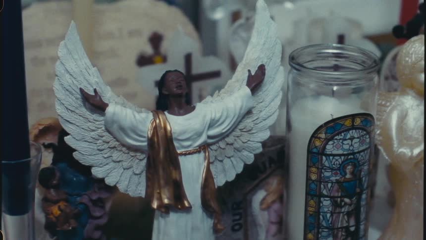 Assortment of religious trinkets including two angel figurines and one 12 hour candle with the image of a saint on the front