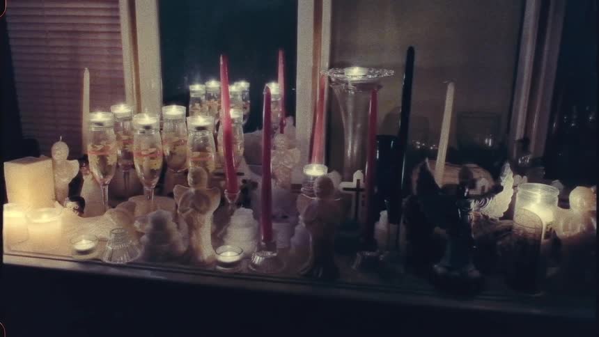 Tall red candles tea cup candles black candles and candles in wine all with a lit wickglasses on a dresser on a room
