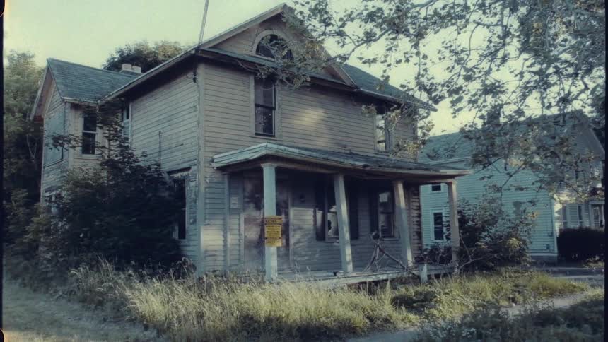 Old abandoned house falling down overgrown lawn badly in need of repair and probably condemned
