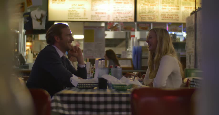 A man and woman sitting at a table in a restaurant talking and smiling