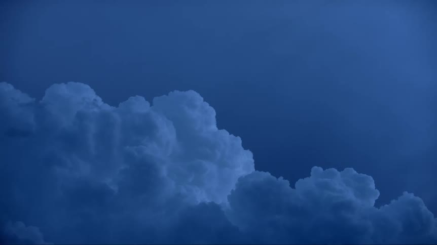 Thick white clouds moving through the evening sky
