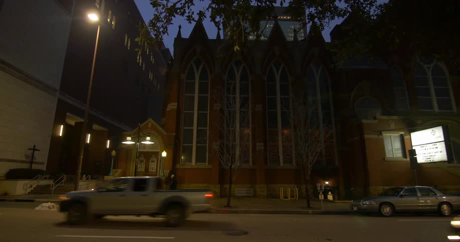 A person walking down a sidewalk in front of a building at night