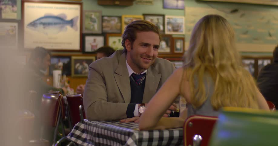 A woman and man converse at a restaurant table