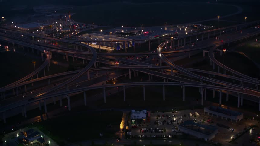 An aerial view of vehicles driving on a freeway and overpasses in a city