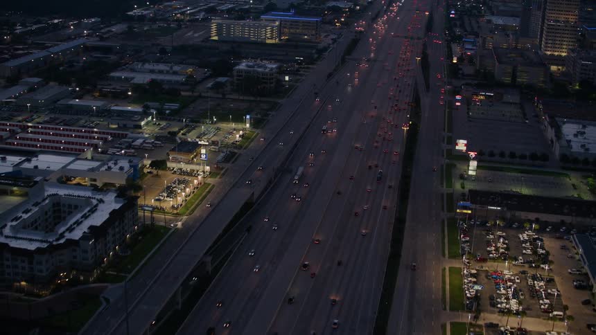 Heavy traffic drives down a multilane street through a city at night