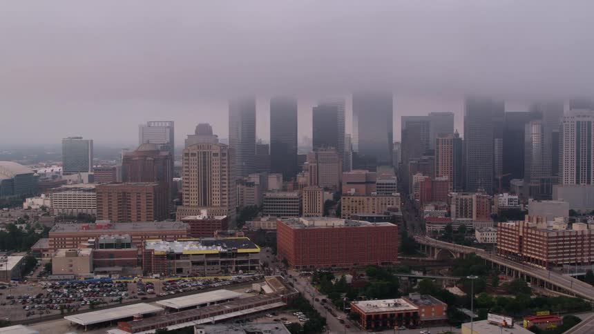 Low lying clouds cover the tops of skyscrapers near stadium
