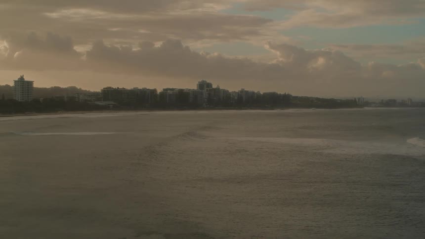 Waves moving on the ocean with buildings in the background