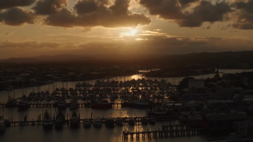 Dozens of boats sit parked in a harbor along the coast