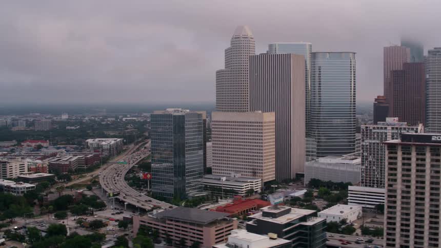 An aerial view of cars driving past high rise office buildings in a city