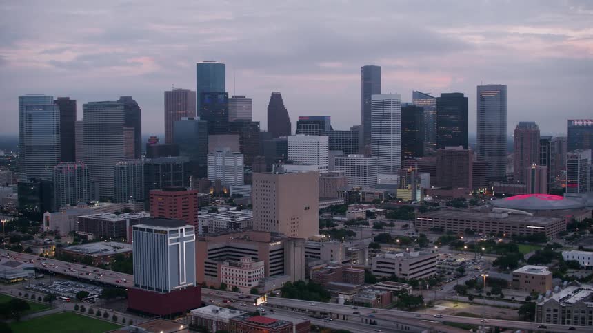 An aerial view of a downtown urban area under mostly cloudy skies at dusk