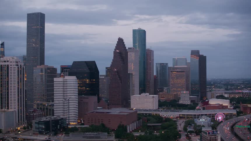 Vehicles drive down a highway past downtown skyscrapers