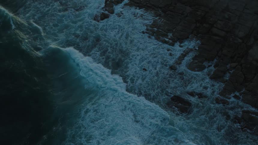 Waves foam as they roll onto rocky shore