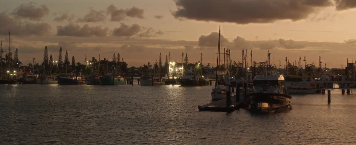 Police boats are docked in a marina among other boats as the sun set in a cloudy sky
