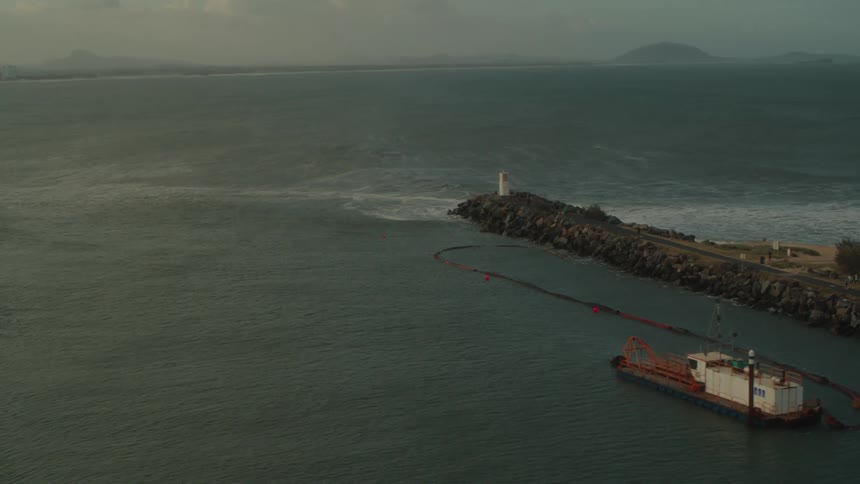 Ocean waves crash onto the shore below lighthouses down long piers