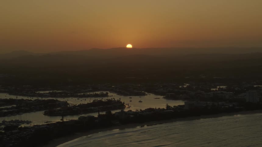 A sunset behind the horizon as seen from an aerial view over a coastal lake