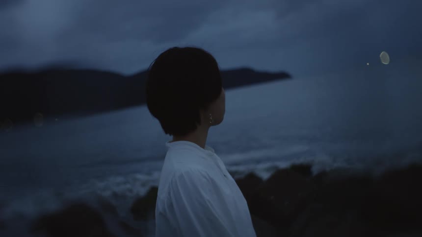 The view is of a kid that is standing in front of the ocean