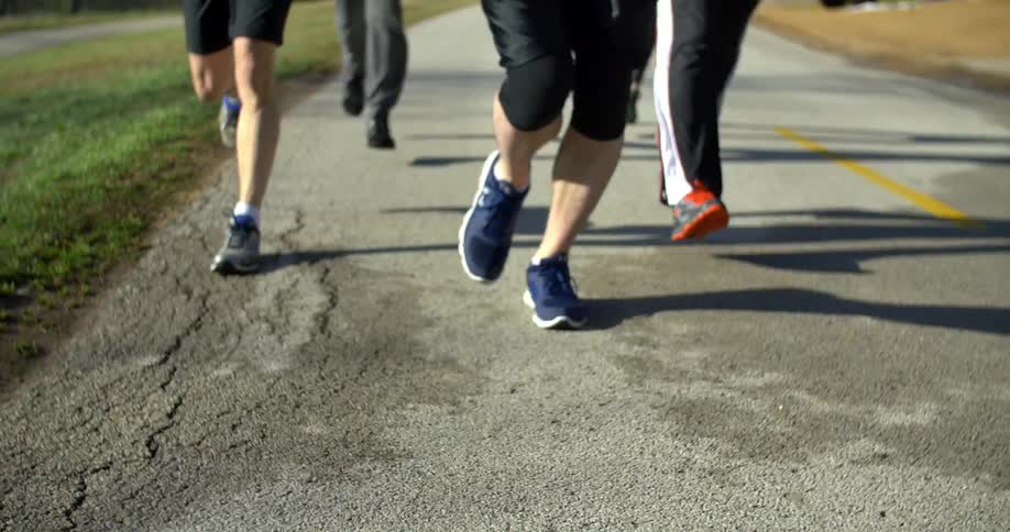 A  group of people jogging down a street on a sunny day