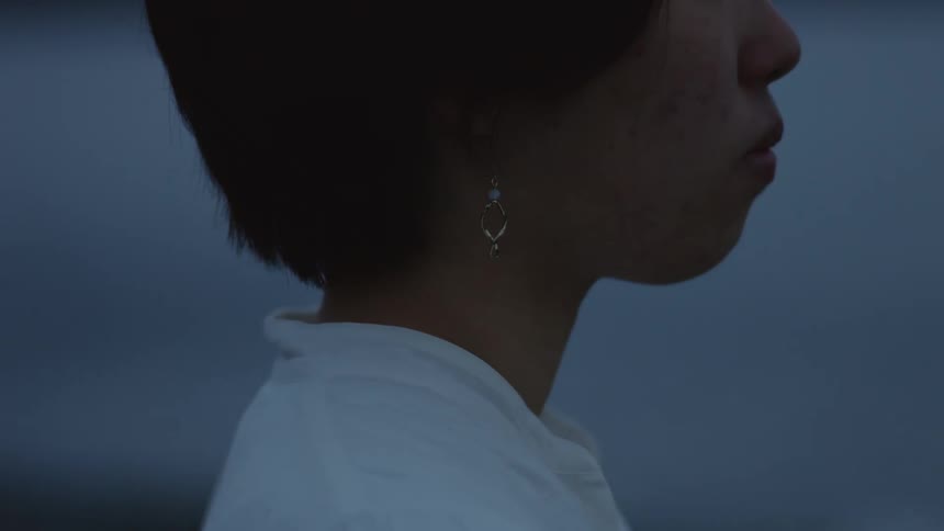 A woman with short black hair and earrings is looking ahead
