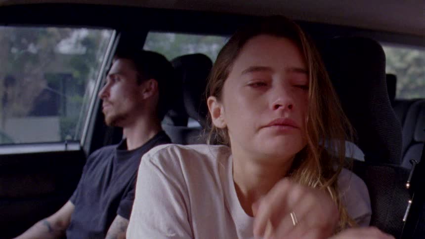 A couple appear upset while sitting in a parked car not speaking
